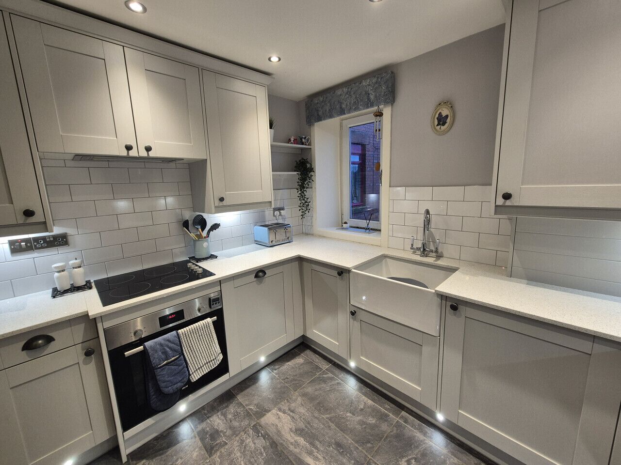 A modern kitchen with white cabinetry, a built-in oven, and a window above the sink.