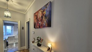 A hallway with a painting of a bull, a small table with a lamp, and a rug.
