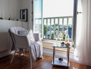 A cozy room with a white chair, a small table with a bowl of fruit, and a view of a balcony with a railing. - 2 bedroom accommodation in Swarthmoor, near Ulverston (Swarthmoor, near Ulverston)