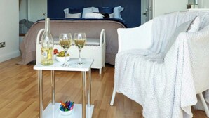 A bedroom with a bed, a white chair, a small table with a bottle and glasses, and a bowl of fruit. - 2 bedroom accommodation in Swarthmoor, near Ulverston (Swarthmoor, near Ulverston)
