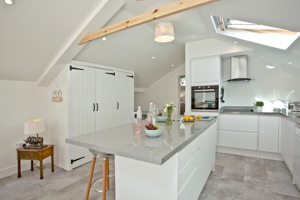 A modern kitchen with white cabinetry, a granite countertop, and a built-in oven.