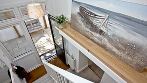 A modern kitchen with a wooden countertop, a painting of a boat on the wall, and a hanging light fixture. - Charming Cottage, Wi-Fi, Parking, Pets Accepted (Newquay)