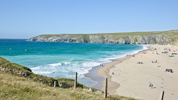 A beach with clear blue waters, sandy shore, and grassy cliffs. - Charming Cottage, Wi-Fi, Parking, Pets Accepted (Newquay)