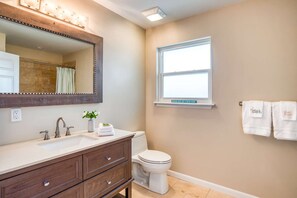 A bathroom with a vanity, a toilet, a window, and a towel rack with towels.