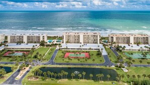 A coastal hotel complex with multiple buildings, a tennis court, and a lake. - Crescent Beach Condos (St. Augustine)