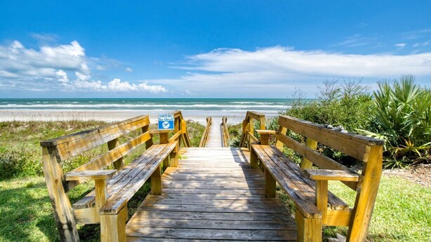 A wooden boardwalk leading to a beach with benches and a sign warning about sea turtles. - Crescent Beach Condos (St. Augustine)
