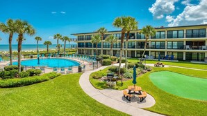 A pool area with lounge chairs, a barbecue setup, and a golf putting green. - Crescent Beach Condos (St. Augustine)