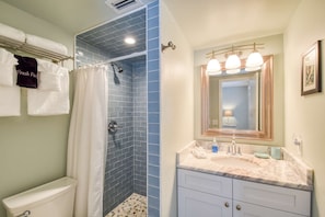 A bathroom with a shower, toilet, and vanity with a mirror.