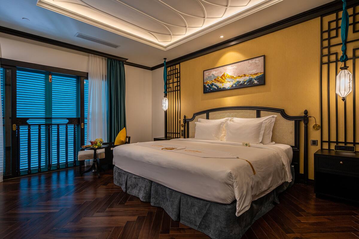 Une chambre spacieuse avec un grand lit, une vue sur l’extérieur grâce à une porte coulissante et un élément décoratif mural.