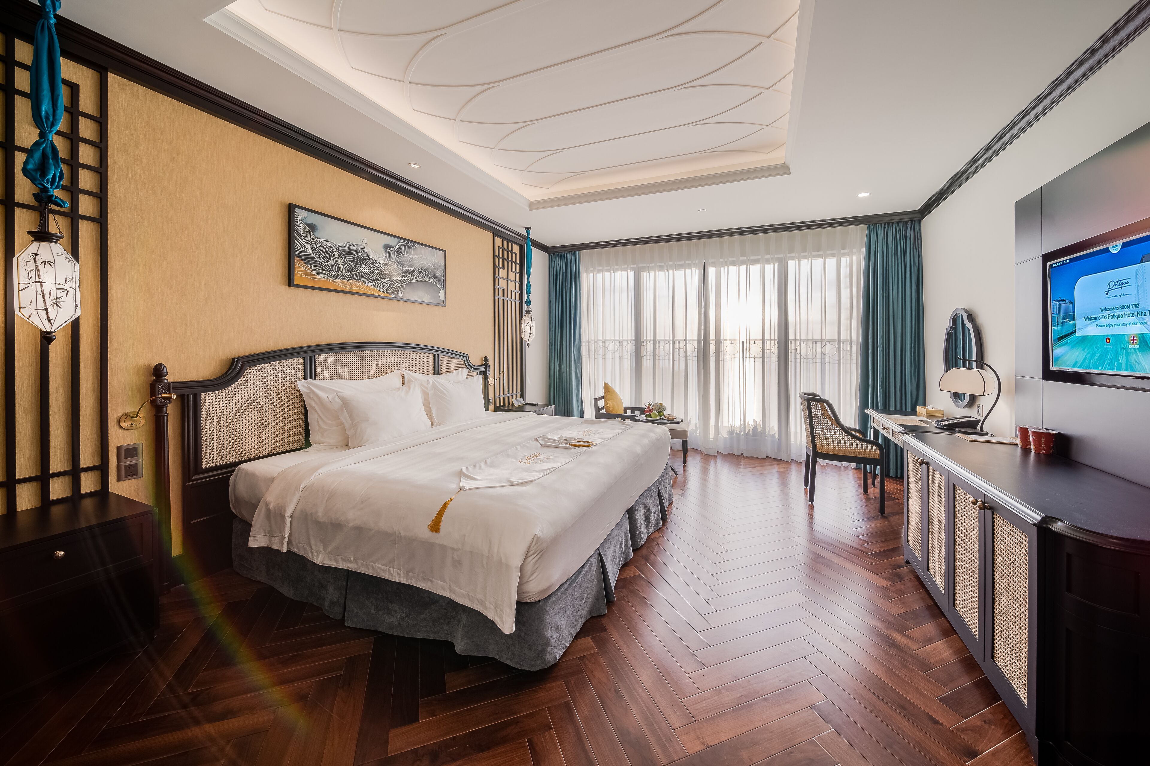 Une chambre d’hôtel avec un grand lit, un bureau, une télévision et un balcon avec des rideaux.