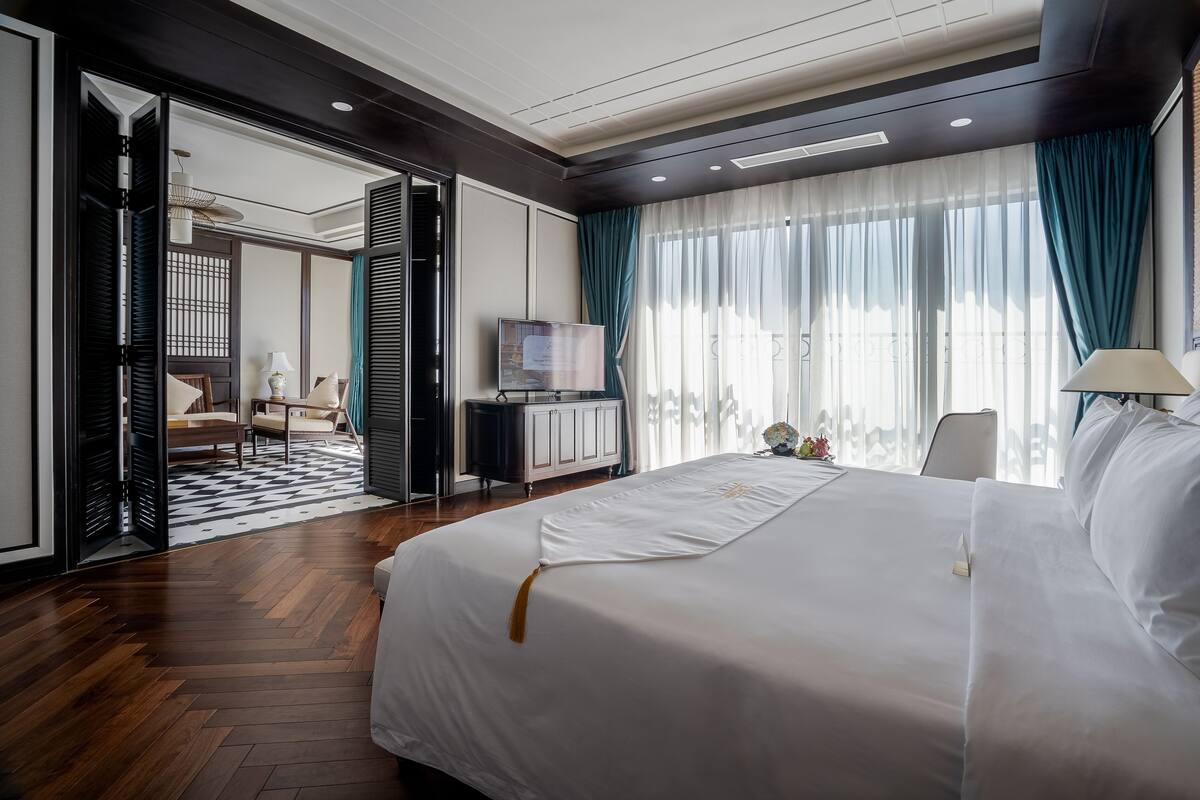 Une chambre d’hôtel moderne dotée d’un grand lit, d’une télévision et offrant une vue sur la ville grâce à de larges fenêtres.