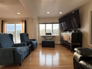 A living room with a piano, a television, and a view of the outdoors.