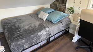 A bedroom with a bed, pillows, a nightstand, a chair, and a wall with anchor decorations. - Worth Every Step to Lake's Edge
Direct Lakefront-Private Docks, Fire Pit, EV Chg (New Fairfield)
