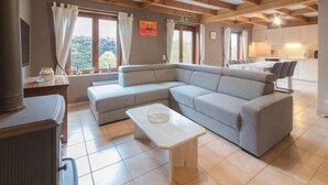 Ein modernes Wohnzimmer mit einem Ecksofa, einem kleinen Couchtisch und einer Küchenzeile im Hintergrund.