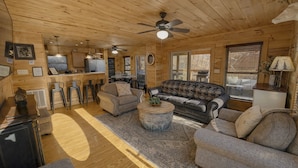 A cozy cabin interior with a wooden ceiling, a sofa set, a dining area, and a television. - Luxe Pool Cabin Near Dollywood & Top Attractions (Pigeon Forge)