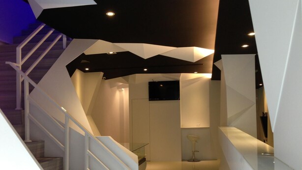 Un interior moderno con una escalera, techo plano con iluminación empotrada y diseño minimalista.
