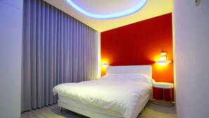 Una habitación de hotel moderna con una cama grande, una mesita redonda y dos lámparas fijadas a la pared.