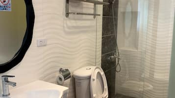 A modern bathroom with a white sink, toilet, and shower. There is a glass shower enclosure and a mirror with a black frame.