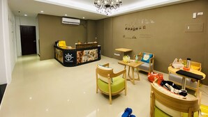 A reception area with a wooden desk, a chandelier, and a wall with photos and text. - Spring Hall (Luye)