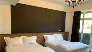 A hotel room with two beds, a large dark wall, a chandelier, and a view of greenery outside. - Spring Hall (Luye)