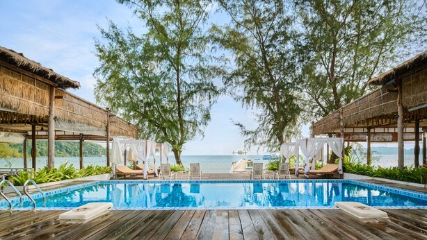 A wooden deck with a pool, lounge chairs, and a view of the sea. - Eden Beach Resort by EHM (Koh Rong Sanloem)