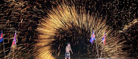 A person standing on a surfboard with sparks flying around, surrounded by flags.