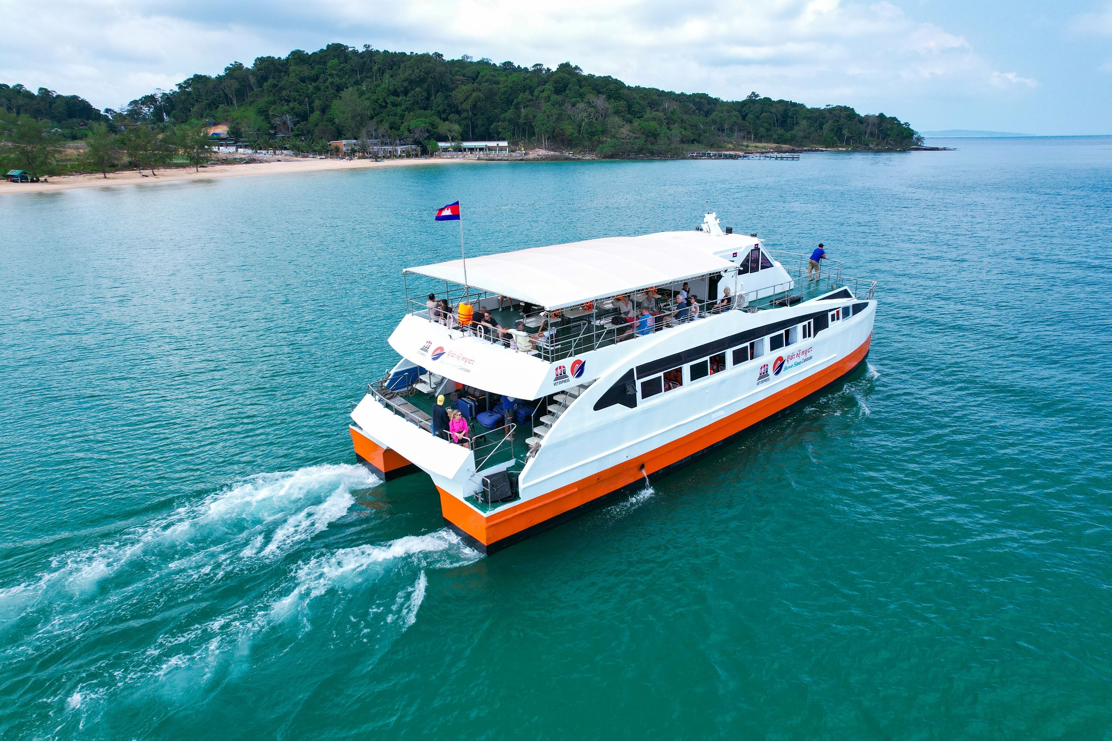 A large boat with a white and orange hull, a covered upper deck, and a flag on top.