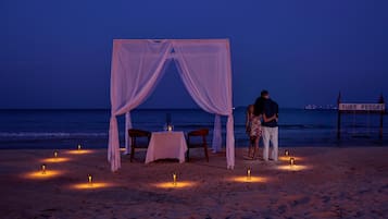 A beachside tent with a table and chairs, candles, and a sign for 'Tube Resort.'