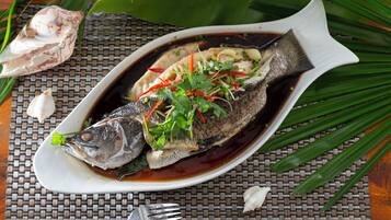 A dish of fish garnished with herbs and vegetables on a white plate.