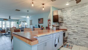 A spacious kitchen with a large island, stone backsplash, and modern appliances. - Beachfront Siesta Key Condo w/ Enclosed Patio (Siesta Key)