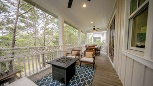 Une véranda couverte avec un foyer, des chaises en bois et un tapis à motifs.
