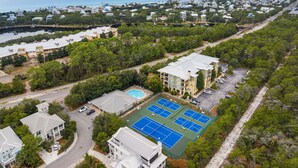 Vue aérienne d’un quartier résidentiel avec un grand bâtiment comprenant plusieurs courts de tennis et une piscine.