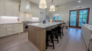 A spacious kitchen with white cabinetry, a large island with bar stools, and pendant lighting. - 4 BR Grayton Beach, private beach, Tesla charger, 2 pools, tennis, & Pickle ball (Santa Rosa Beach)
