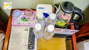 A tray with a remote control, a water dispenser, a kettle, and several water bottles on a table with a menu. - Arina Boutique Kampot (Kampot)
