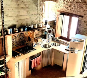 Una cocina compacta con estufa a gas, dos fregaderos y un refrigerador.