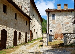 Un edificio rústico de piedra con ventanas de arco y un camino de grava que conduce a una entrada con portón.