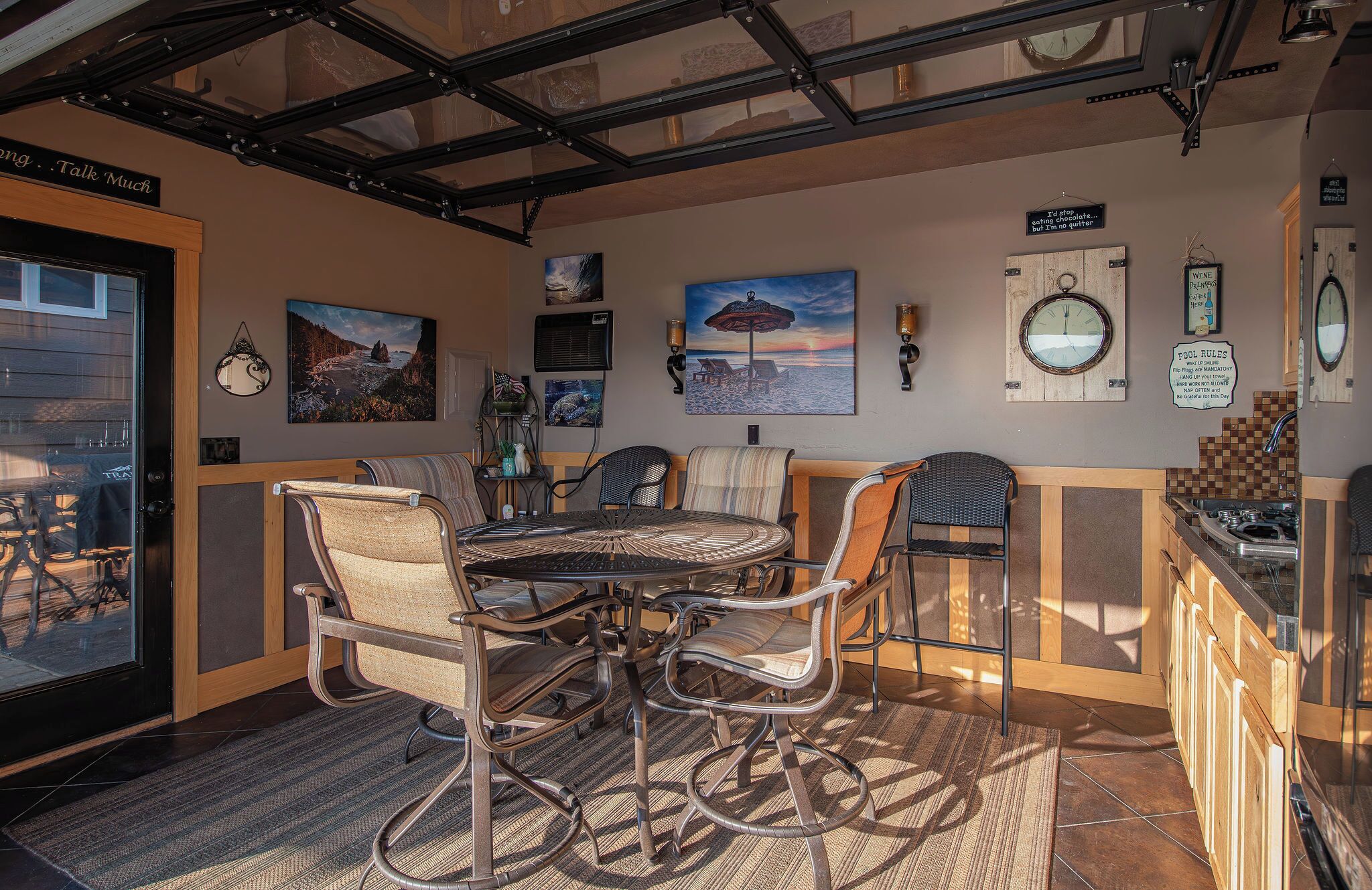 A cozy dining area with a round table and chairs, a wooden counter with a sink, and various wall decorations including a clock and framed pictures.