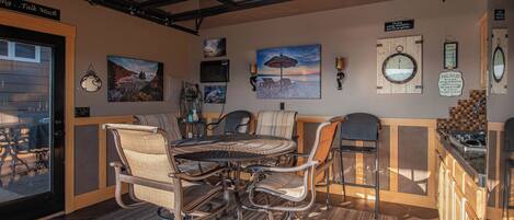 A cozy dining area with a round table and chairs, a wooden counter with a sink, and various wall decorations including a clock and framed pictures.
