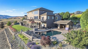 A large two-story house with a pool, outdoor seating, and a view of the hills. - Riverview Retreat: Incredible Views, Heated Pool, Spa, Theater Room & More! (East Wenatchee)