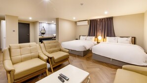 Una habitación de hotel con dos camas, un sofá, una mesa de centro y un televisor.