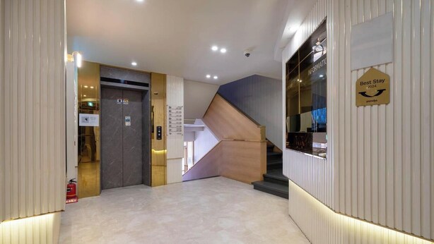 Un moderno hall de hotel con un diseño de escalera único, una recepción y un letrero que dice 'Best Stay 2024'.
