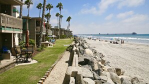 A beachfront hotel with a pool area, palm trees, and a view of the ocean and pier. - F110-Sea Pointe, North Coast Village 2 queen bdrm (Oceanside)