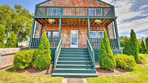 A two-story wooden house with a balcony, a front door, and a staircase leading to the entrance.