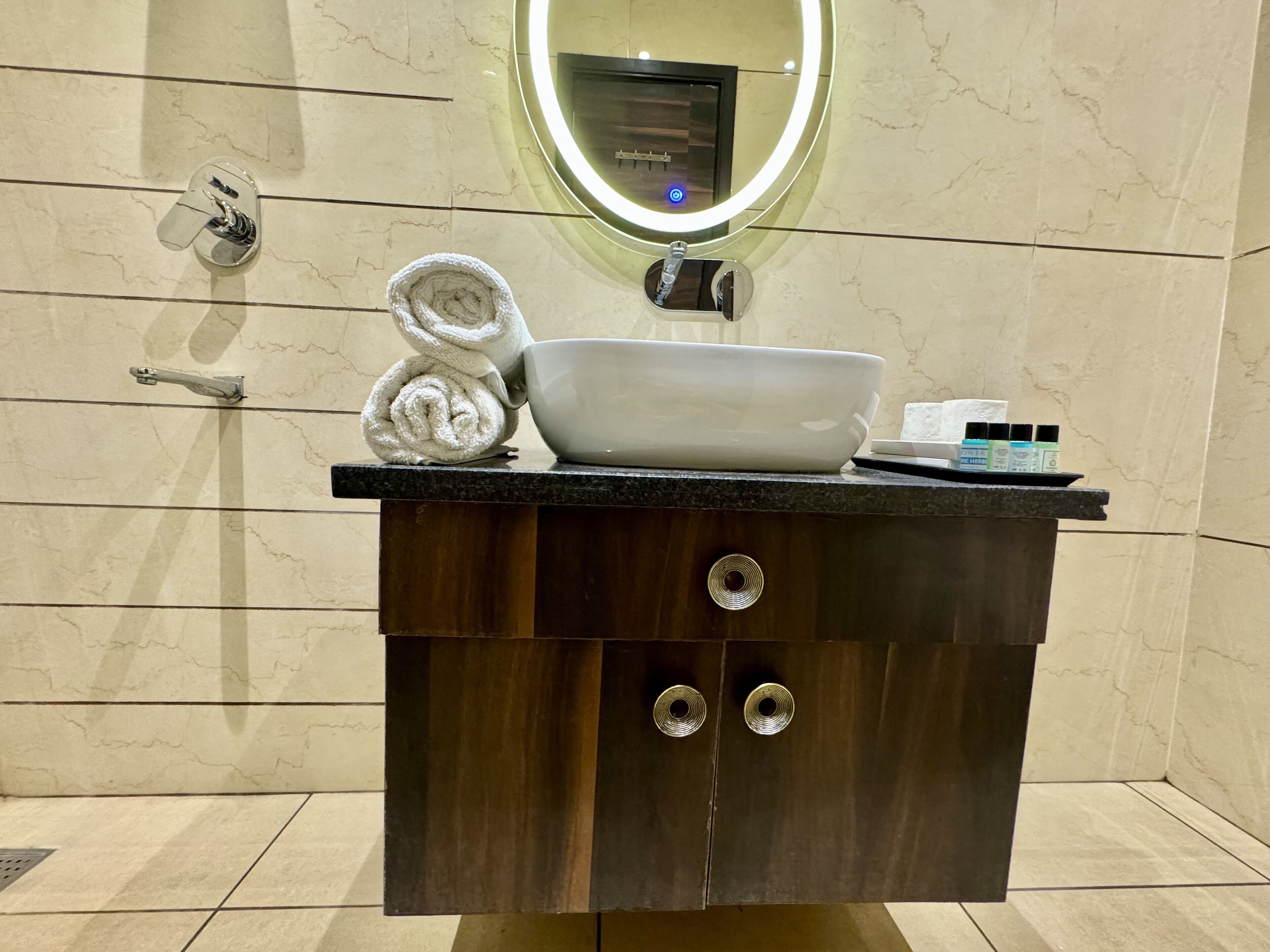 A bathroom vanity with a white sink, a towel, and toiletries.