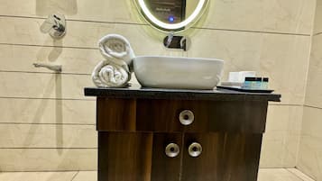 Uma toucador de banheiro com pia branca, toalha e produtos de higiene.