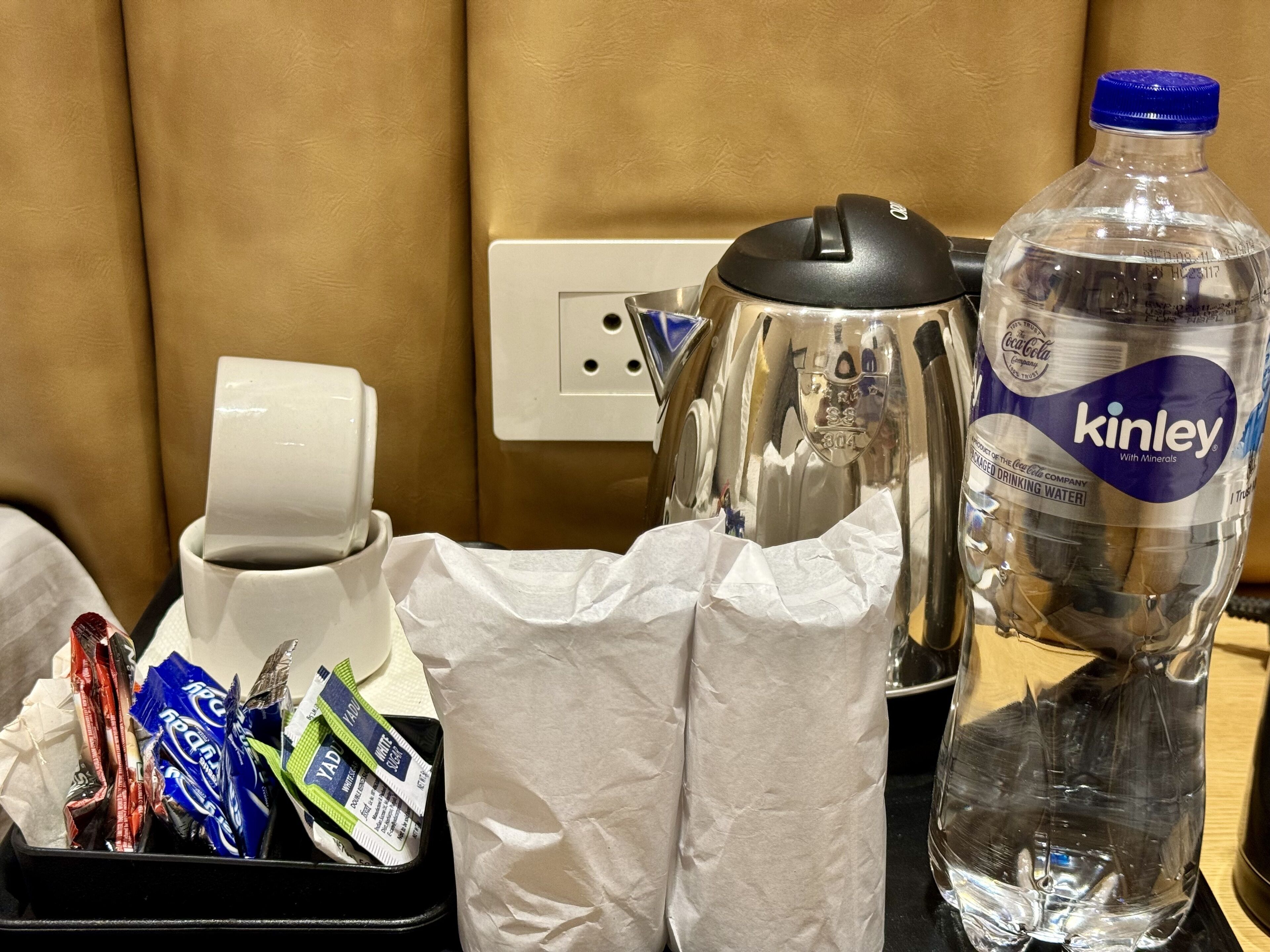 Habitació d'hotel amb cafetera, ampolla d'aigua i envasament de llaminatures.