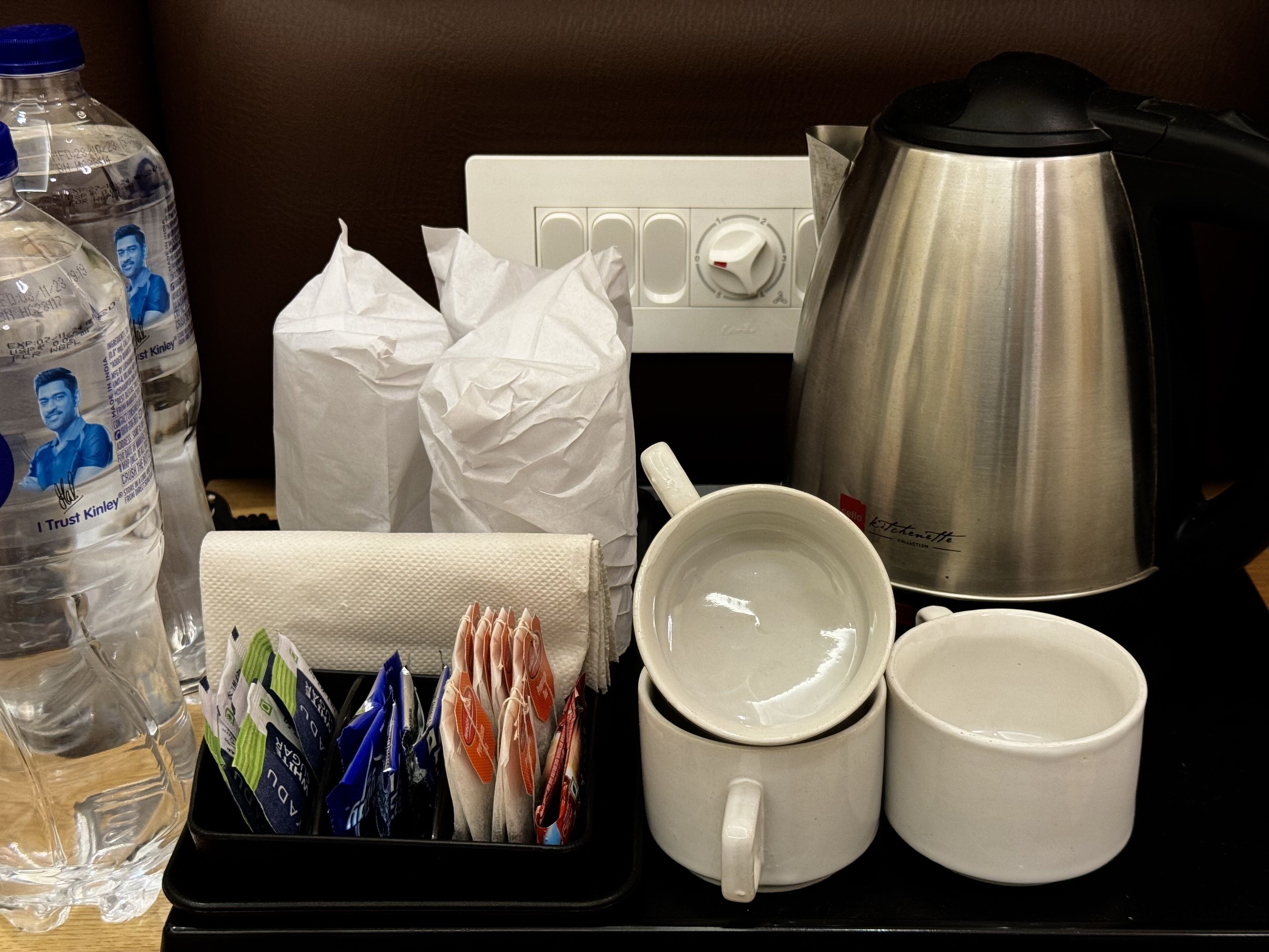 Una bandeja con una botella de agua, pañuelos de papel, una cafetera y dos tazas.