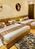 A hotel room with two beds, a large rug, and a wall-mounted artwork.