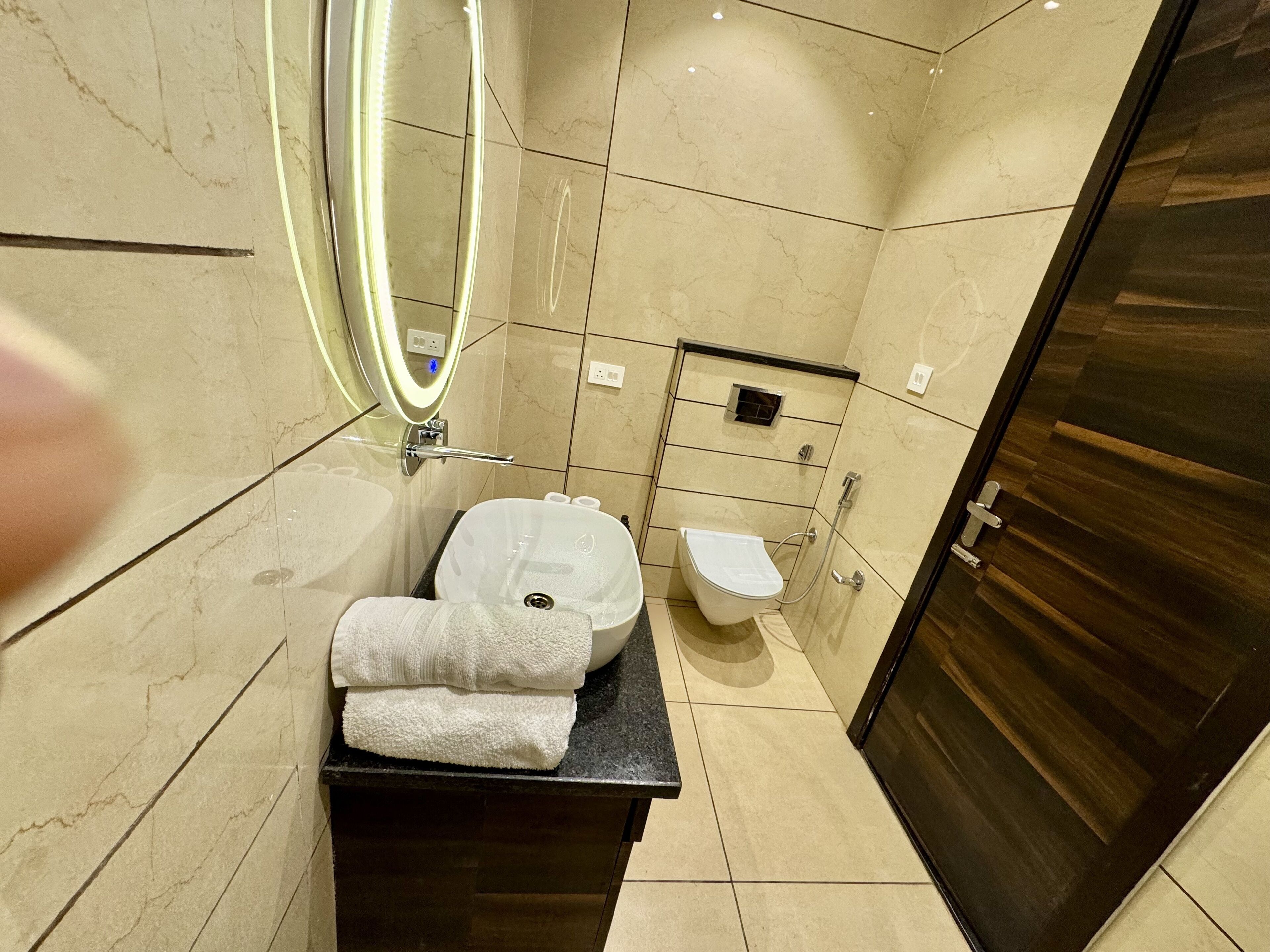 A modern bathroom with a large mirror, a sink, a toilet, and a shower area.