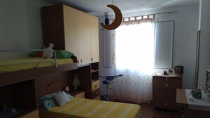 Ein Kinderzimmer mit Etagenbetten, einem Schreibtisch und einem Fahrrad.